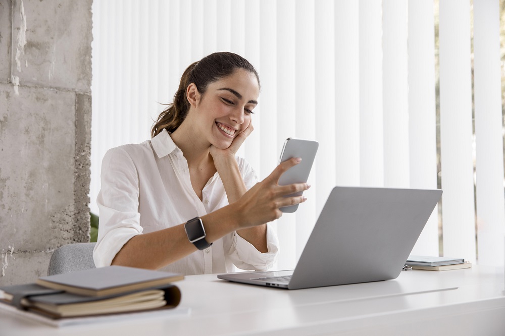 Woman with a mobile and a laptop in an office